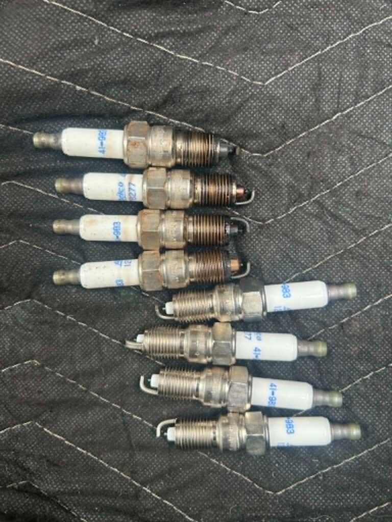 Old and new spark plugs from a MerCruiser 8.1 spark plug and belt replacement in Fort Myers